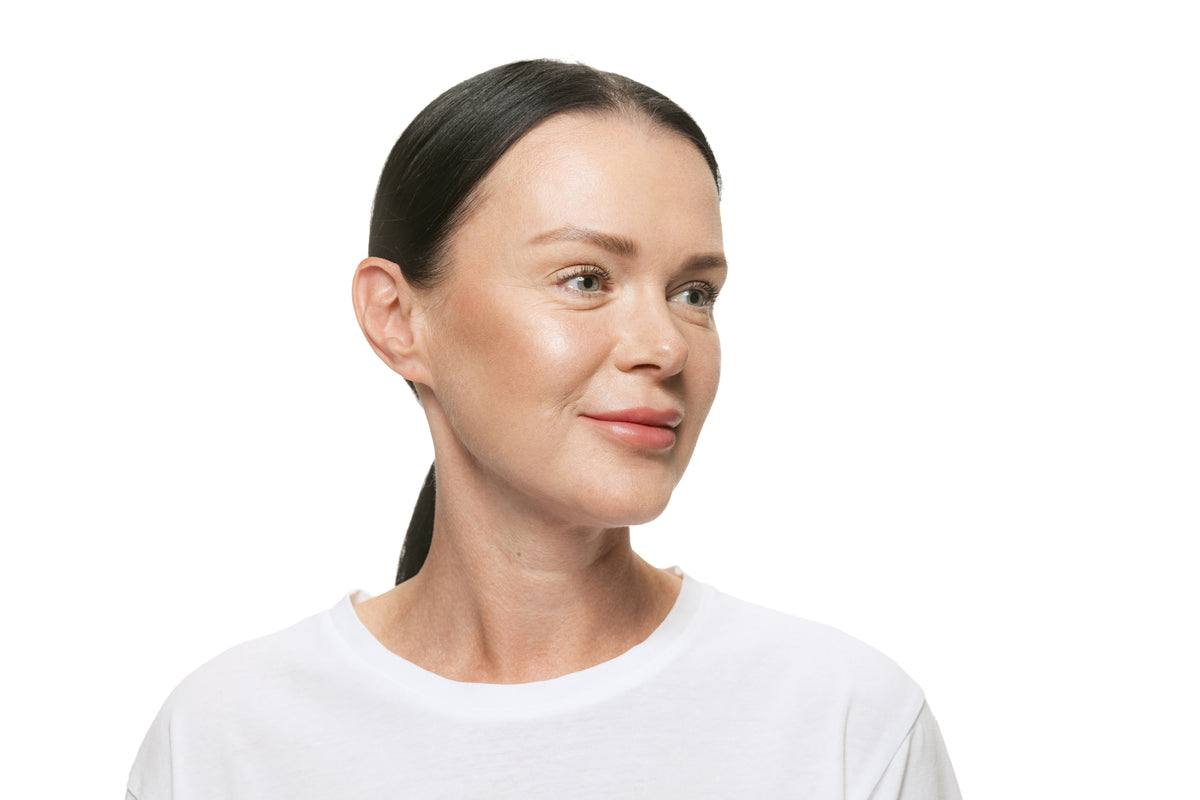 Woman in her forties in a white t-shirt, smiling, looking away